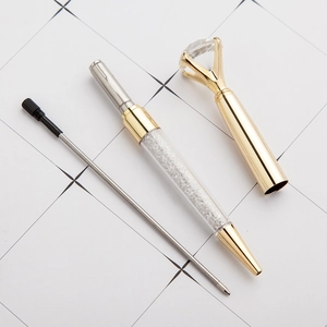 Disassembled golden metal ballpoint pen with a large diamond top and crystal filling