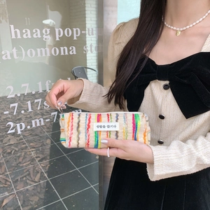 Close-up of textured canvas pouch with colorful stripes and minimalist Korean woven label