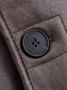Macro detail of brown leather texture and black button on a French style jacket