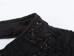 Close-up of black textured fabric featuring elegant sequin embroidery details on evening dress