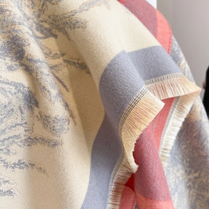 Close-up of tricolor beige and brown knit scarf with fringe detail and soft cashmere-like texture