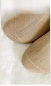 Macro detail of hand-linked seamless toe on light beige combed cotton ribbed socks