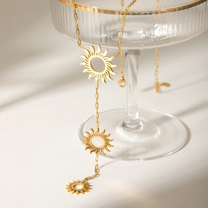 Detailed close-up of golden hollow sun pendant necklace on a crystal glass