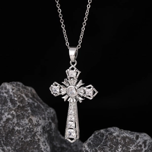 Dettaglio macro della collana con croce in argento e zirconi bianchi su sfondo di pietra scura