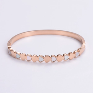 Detail view of heart-shaped white mother of pearl inlays on a rose gold bangle