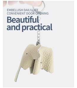 Hand holding a cute beige genuine leather elephant keychain for car keys and bags