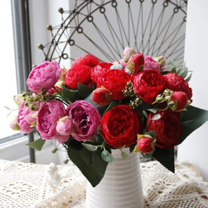 Detail of red and pink artificial silk roses in a white vase with vintage indoor decor