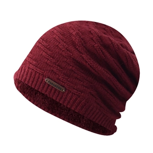 Detail view of burgundy knitted beanie with warm fleece lining and metal logo plate