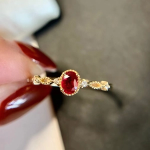 Close-up of gold ring with oval red gemstone and delicate lace-edged border