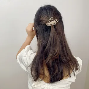 Detail view of a golden rhinestone swan hair clip on a model's half-up hairstyle