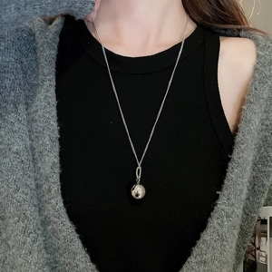 Minimalist silver spherical pendant necklace shown on a model with a knit sweater background