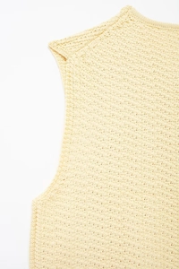 Detailed macro view of cream knit vest showing intricate diamond mesh crochet texture