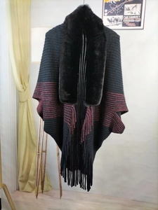 Detail of knit shawl featuring faux fur collar and fringe hem in black and red contrast