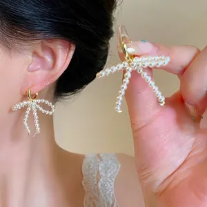Detail of elegant bow earrings crafted with small pearls and a gold-tone metallic hook