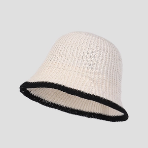 Close-up of cream knit bucket hat with black contrast trim and woven texture
