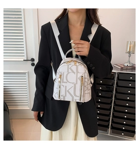 Close-up of white fashion backpack featuring letter print and gold metal zipper details