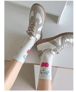 Detail of white cotton socks with pink cherry embroidery and blue text with casual sneakers