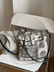 Detail view of two beige cotton linen tote bags with paisley and wavy geometric patterns