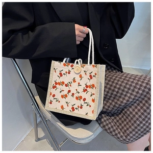 Detailed shot of floral canvas handbag with rose prints, woven handles and wooden button