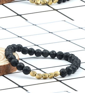 Detail of volcanic lava stone beads and irregular gold metal accents on elastic bracelet