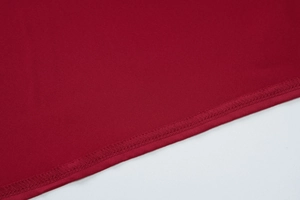 Macro shot of high-quality stitching and hem detail on the dark red formal evening dress