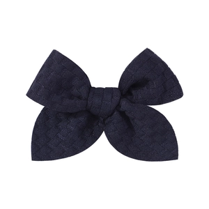 Detail of navy blue knitted bow hair clip with textured square grid pattern fabric