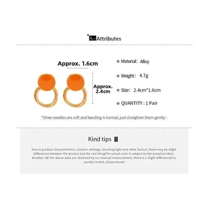 Detail view of orange enamel hoop earrings with gold twist texture and silver needles