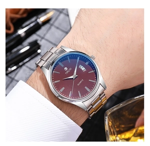 Detail of men's steel watch with red dial and calendar display on a wrist