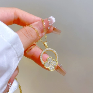 Detailed macro view of a gold-toned titanium steel four-leaf clover pendant with zircon inlay