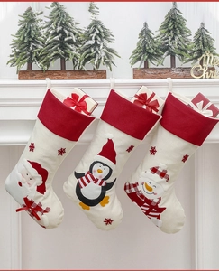 Three Christmas stockings with Santa, penguin, and snowman patterns hanging on a white fireplace