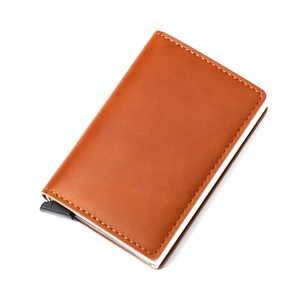 Detail of brown leather RFID card holder with visible stitching and pop-up slide mechanism