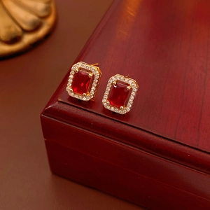 Detail of red square gemstone earrings with diamond halo on a red wooden jewelry box