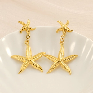 Detailed view of gold starfish earrings with fine textures on a white shell tray