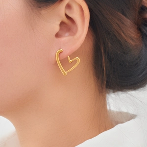 Gros plan d'une boucle d'oreille cœur dorée élégante portée par un mannequin, fini poli