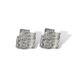 Detailed macro view of irregular geometric earrings with hammered silver texture and finish