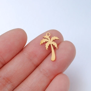 Golden stainless steel palm tree pendant charm for DIY jewelry being held for scale