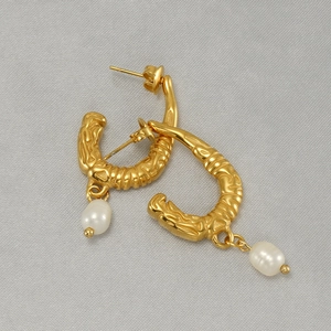 Detailed view of gold textured U-shape earrings with elegant white teardrop pearls