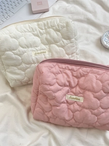 Quilted cloud-patterned makeup bags in cream and pink colors with top zipper closures