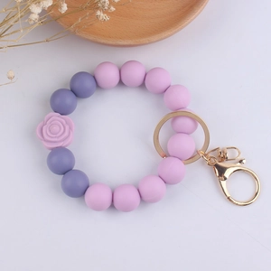 Detail of purple silicone bead bracelet keychain with rose charm and gold hardware