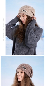 Detail of light coffee knit beanie featuring textured hollow patterns and brand logo label