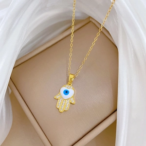 Close-up of golden Hamsa hand pendant with blue eye and sparkling crystal rhinestones