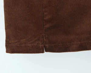 Close-up of caramel corduroy fabric texture with detailed hem slit and stitching