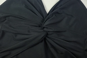 Detail view of V-neck center knot and pleated texture on black two-piece skirt set