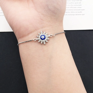 Detailed shot of an evil eye sun charm bracelet with blue stones on a box chain