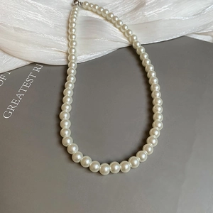Flat lay of a classic white pearl necklace with silver clasp on elegant silk fabric