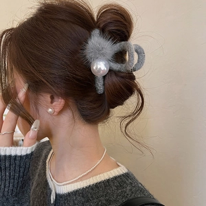 Detail view of gray plush hair claw clip with large pearls worn by a model