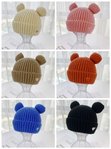 Detail of knitted beanie with bear ears and heart embroidery in six vibrant colors