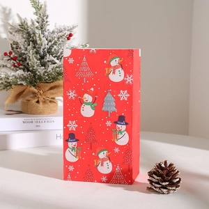 Detail view of red Christmas paper gift bag with snowman and tree print in a festive setting
