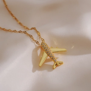 Macro shot of gold airplane pendant necklace with pave-set rhinestones on silk