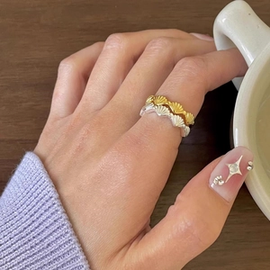 Nahaufnahme goldener und silberner Muschelringe an Fingern, die eine Tasse halten